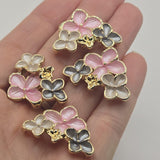 Package of four beautiful pink, gray, and pearl white enamel flower 2 hole slider beads in a polished bright gold finish. Each decorative focal bead features three dimensional flowers with soft enamel petals, tiny gold centers, and intricate gold accents. The romantic floral color combination creates an elegant botanical appearance for handmade bracelets, necklaces, bead weaving, bridal accessories, and coordinated jewelry designs.
