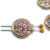 Detailed view of bright gold round filigree slider beads featuring delicate openwork patterns and raised floral embellishments. Soft pastel enamel in blush pink, pearl white, and silvery gray creates beautiful contrast against the polished gold metal. The circular focal beads combine decorative cutout details with small dimensional gold flowers, making them attractive components for handmade bracelets, necklaces, bead weaving, and romantic botanical accessories.