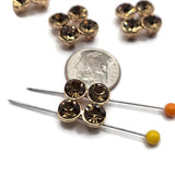 Close-up of smoked topaz rhinestone slider beads in a polished bright gold finish. Four round faceted rhinestones form a balanced square cluster resembling a four-petal flower. The rich smoky brown stones reflect warm amber, bronze, and golden tones, creating beautiful sparkle against the reflective gold settings. Decorative 2 hole focal beads for bracelet making, necklaces, and bead weaving.
